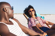 © wavebreak3 - Happy african american couple sitting in deckchairs holding hands on sunny beach