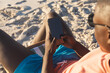© wavebreak3 - African american man in sunglasses sitting in deckchair using smartphone on sunny beach