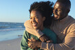 © wavebreak3 - Happy african american couple embracing on sunny beach by the sea