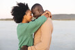 © wavebreak3 - Happy african american couple embracing and smiling on beach at sundown