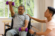 © WavebreakMediaMicro - Diverse male physiotherapist advising and senior male patient in wheelchair using dumbbells