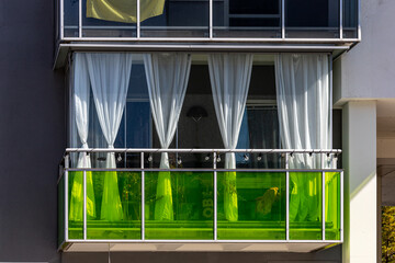 Stockholm, Sweden A balcony in a residential building with green glass and curtains.