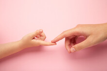 Mother Holding Daughter Hand On Pink Background.