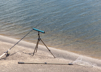 Sticker - Fishing rod and landing net on the concrete shore of the lake