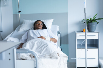 Wall Mural - African american female patient lying on bed and looking away in hospital room