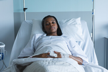 Wall Mural - Portrait of african american female patient with braids, lying in bed at hospital