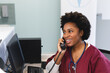 Happy african american female doctor wearing scrubs and stethoscope, talking on phone at hospital