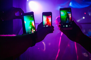 Wall Mural - men's hands with smartphones take pictures of a dancer's ass in a nightclub