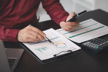 Wall Mural - Business man pointing to a pie chart document showing company financial information, He sits in her private office, a document showing company financial information in chart form. Financial concepts.