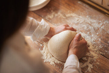 Female baker kneads dough, making tasty and airy bread by herself. Girl baking handmade bread at home