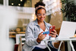 © (JLco) Julia Amaral - Woman smiling and using mobile for online payment
