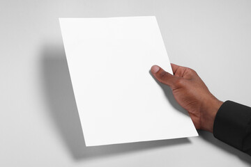 Wall Mural - african american man holding sheet of paper on white background, closeup. mockup for design