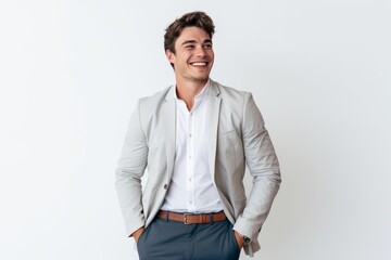 Wall Mural - Portrait of a smiling young businessman standing with hands in pockets isolated on a white background