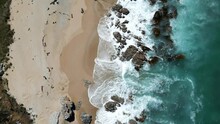 Top View Of The Foamy Sea Waves Hitting The Rocks And The Sandy Shore In Otago, New Zealand