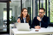 © bnenin - Female and male businesspeople sitting in front of the laptop at the office.