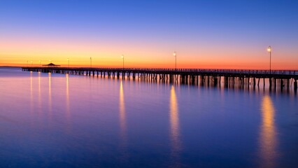 Sticker - a pier is lit up at night by the water's edge