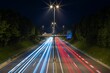 Long exposure of a roadway illuminated by the headlights of passing cars on a dark night