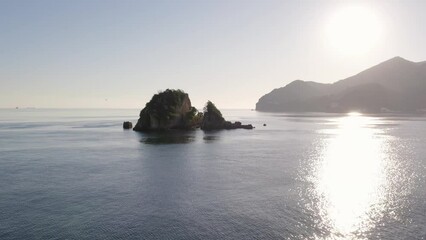 Sticker - Aerial of big rock stacks with big mountains and the sandy shore in the sunny background