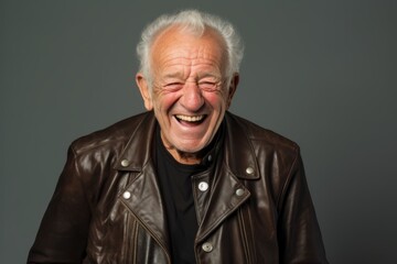 Portrait of a happy senior man in leather jacket on gray background