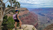 Woman next to old dry tree with scenic aerial view from Skeleton Point on South Kaibab hiking trail, South Rim, Grand Canyon National Park, Arizona, USA. Colorado River weaving through rugged terrain