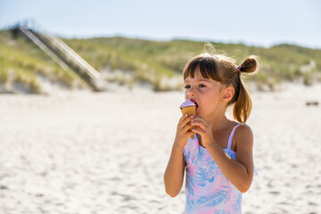 Little girl eating ice-cream on a beach