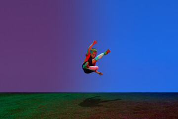 Wall Mural - Male beginner soccer player in sports uniform in action, motion with ball over dark blue background in neon. Concept of sport, health, action, ad