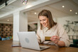 © Sandra - One young business woman holding credit card and shopping online on laptop, modern consumer concept