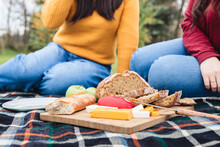 Unrecognizable Friends Having Cheeseboard During Picnic