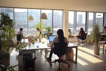 Bright coworking space, several people working on computers. Generative IA.