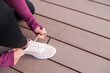 Female hands tying shoelace on running shoes before practice. Runner getting ready for training. Sport active lifestyle concept.