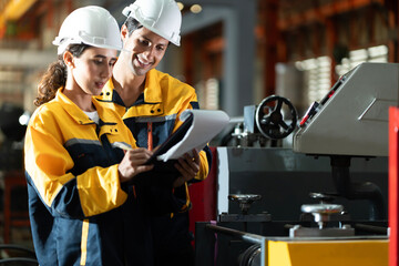 Wall Mural - Two professional engineer,worker,technician use clipboard discuss work, walk in steel metal manufacture factory plant industry. Black African American man and woman wear hard hat check quality machine