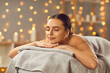 Relaxed attractive young woman relaxing in beauty spa salon. Portrait of brunette girl lying with closed eyes enjoying massage and spa. Beauty treatment, wellness, body care concept