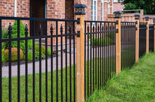 Wrought Iron Fence. Metal Black Fence Around House With Green Lawn. Street Photo