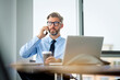 © gzorgz - Handsom businessman sitting in the office and using mobile phone and laptop for work