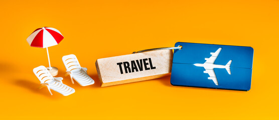 Fototapete - Written travel on a wooden block, Vacation concept, Luggage tag for airplane, Sun lounger and umbrella miniature, Beautiful yellow background, Panorama