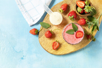 Wall Mural - Fresh milk, strawberry drinks on wooden board on a stone background, protein shake with fresh berries. View from above. Copy space.