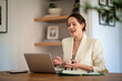 © sepy - Smiling young businesswoman with laptop sitting at home and having video conference