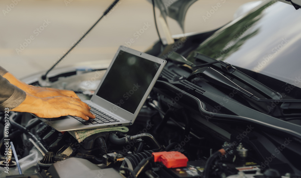 Young mechanic opens the bonnet to inspect the engine for damage and does professional maintenance. He puts on his uniform and inspects.