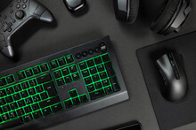 Green Lit Keyboard Surrounded By Various Modern Wireless Gadgets