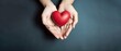 © YuDwi Studio - hands holding red heart, health care, love, organ donation, mindfulness, wellbeing, family insurance and CSR concept, world heart day, world health day, world mental health day, praying concept.