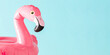 Cute inflatable pink flamingo toy. Summer beach composition. Inflatable mini flamingo on pastel blue background, pool float party, trendy summer concept. Flat lay, top view, copy space