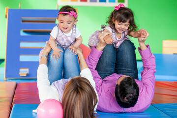 Wall Mural - Young parents playing with their daughters. Early stimulation for toddlers and children concept.