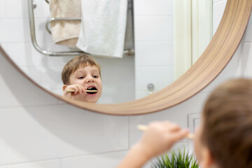 Wall Mural - cute 5 years old boy brushing teeth with bamboo tooth brush in bathroom. Image with selective focus