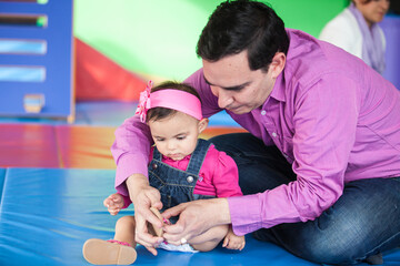 Wall Mural - Young father playing with his baby daughter. Early stimulation for toddlers concept.