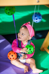 Wall Mural - Beautiful ten months baby girl playing with colorful balls. Early stimulation for toddlers concept.