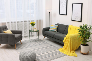 Wall Mural - Spring atmosphere. Stylish living room interior with comfortable furniture and bouquet of beautiful yellow tulips