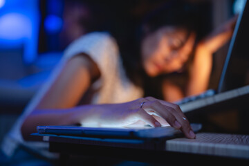 Late-night freelancer, Dedicated Asian woman working overtime on laptop computer, meeting deadlines in the sleepy Night, Businesswoman burning the midnight to working hard, sleep at working desk