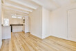© Casa imágenes - an empty living room with wood flooring and white paint on the walls there is a kitchen in the background