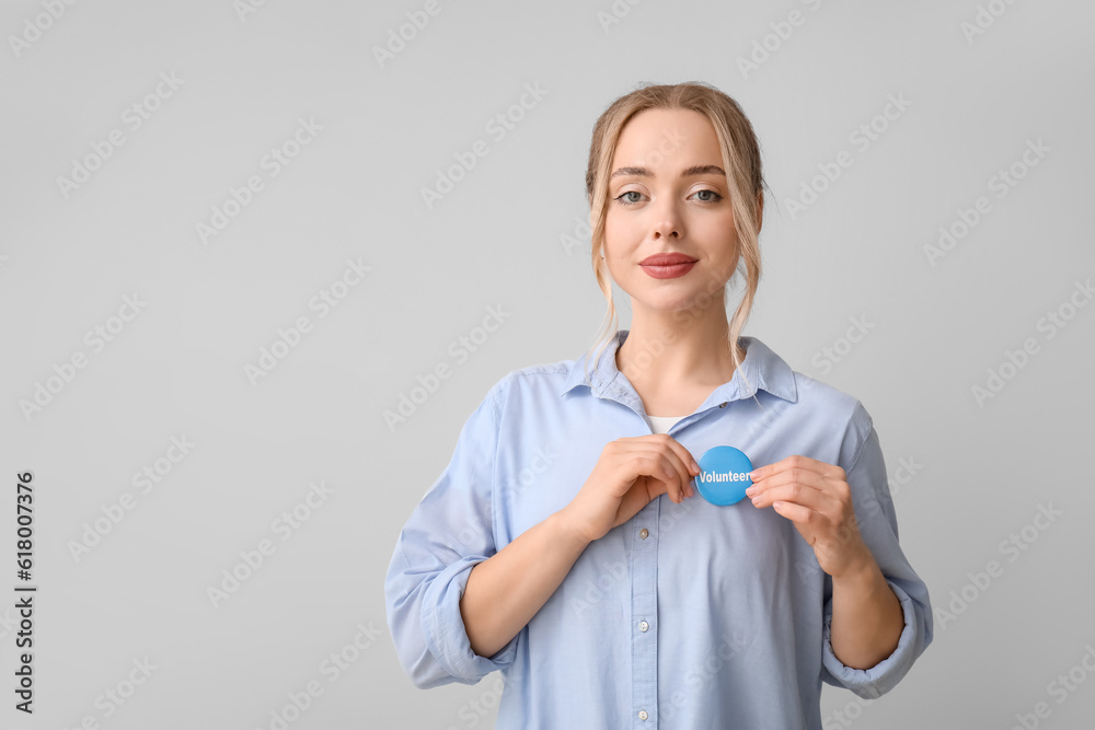 Female volunteer with badge on grey background