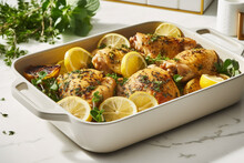 Baking Dish Full Of Chicken In Lemon Sauce And Some Herbs With Delicious Sauce, Giving It Juiciness And Flavor, Freshness And Tanginess
